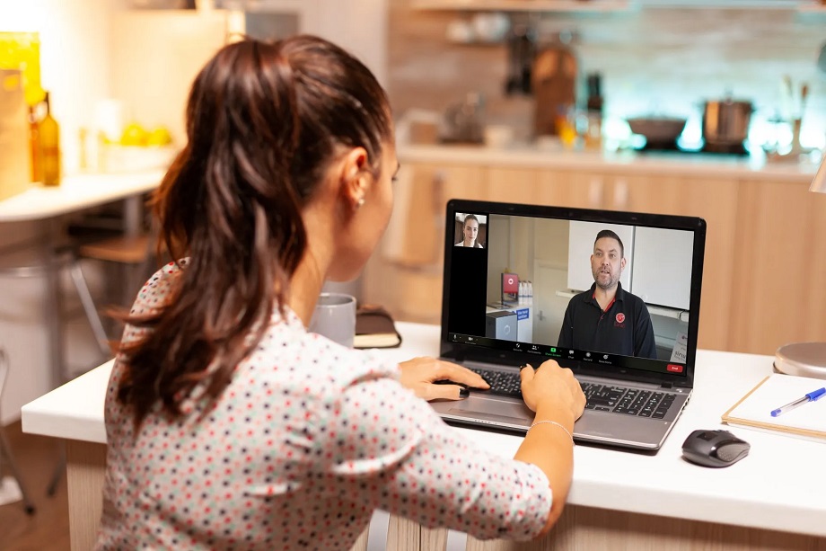 A home-owner on their laptop in the their kitchen speaking to an engineer online.